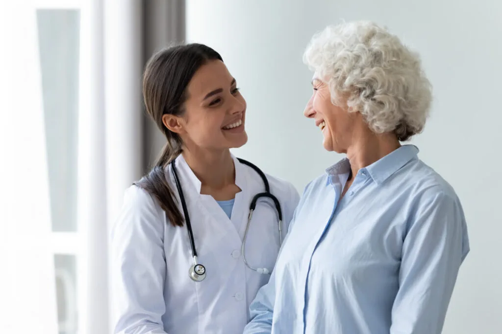caring nurse consulting with elderly woman for varicose vein treatment by professional vein doctor
